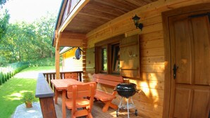 A wooden cabin with a porch, outdoor seating, a grill, and a door. - Cozy Cottage With a Huge Garden, Jaroslawiec (Postomino)
