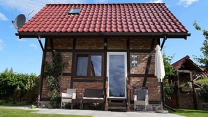 Ein zweistöckiges Backsteinhhaus mit roten Ziegeln und einer Satellitenschüssel sowie einem kleinen Fenster.