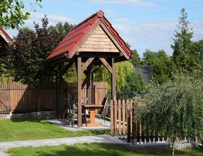 A wooden gazebo with a red roof, surrounded by a wooden fence and greenery. - Holiday Home, Kolczewo (gmina Wolin)