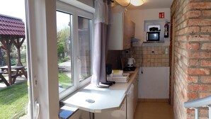 Eine kleine Küche mit Fenster, einer Mikrowelle und einem Spülbecken.