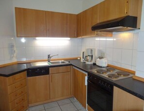 Una cocina con armarios de madera, lavavajillas, estufa y cafetera.