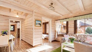 Een houten cabin met een eethoek, een bank en een raam met uitzicht op de natuur.
