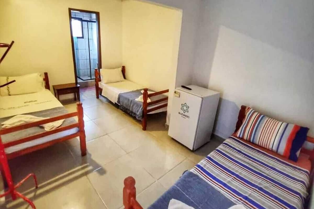 A room with a bed, a desk, a chair, and a small refrigerator.