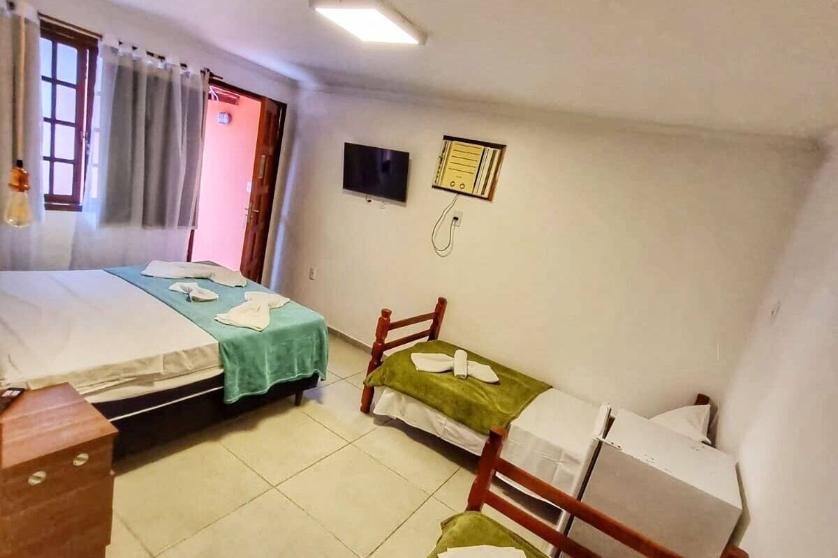 A small, clean room with two beds, a TV, and a simple wall-mounted heater.