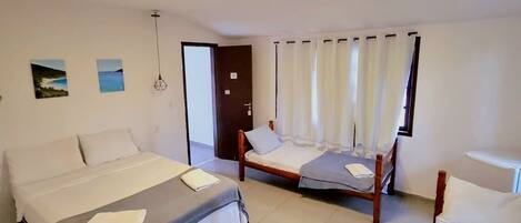 Ein Hotelzimmer mit einem großen Bett, einem kleineren Bett, einem Sessel und einem Sofa.