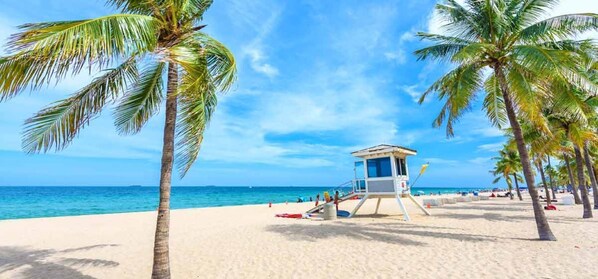 A beach with a lifeguard tower, palm trees, and a clear blue sky. - Waterfront, 7s Hot Tub, 5 Min to Sawgrass Mall - Biggest Outlet Mall in US (Sunrise)