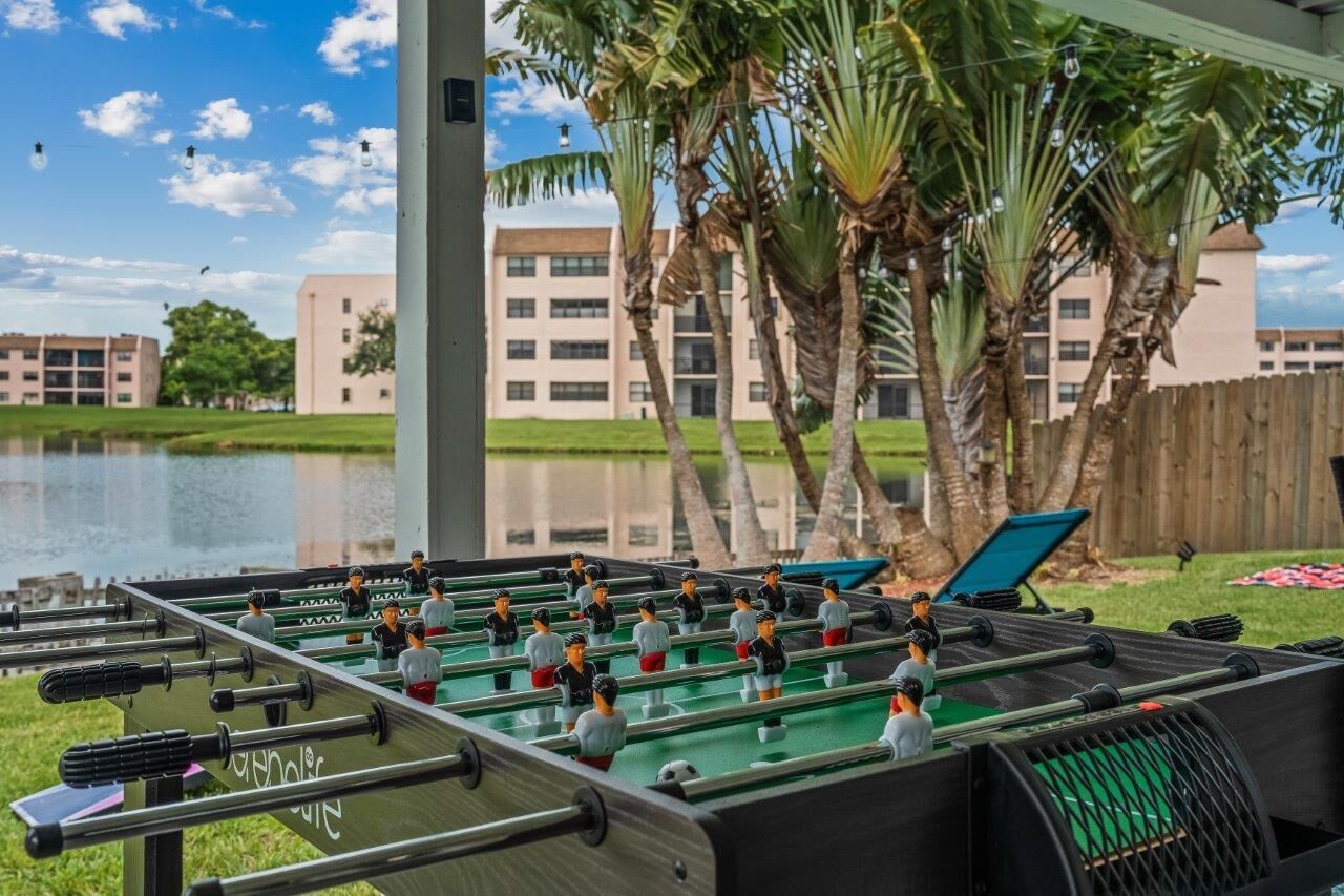A foosball table set up outdoors with a view of a building and palm trees in the background.