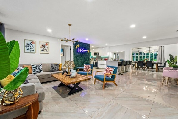 A modern living room with a sofa, chairs, a coffee table, and a neon sign. - Waterfront, 7s Hot Tub, 5 Min to Sawgrass Mall - Biggest Outlet Mall in US (Sunrise)