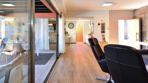 A modern living room with a large window, a dining area with a table and chairs, and a kitchen in the background. - Holiday Home, Maspalomas (San Bartolomé de Tirajana)