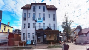 A multi-story building with a sign for a business on the ground floor. - Apartment Right by the Sea, Ustronie Morskie (Ustronie Morskie)