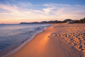 Ein Strand mit freiem Blick auf den Ozean und entfernte Berge.