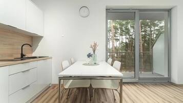 Una cocina moderna con armarios blancos, encimera de madera y grifo negro.