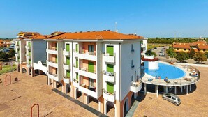 Un hôtel à plusieurs étages doté de balcons, d’une piscine et d’un parking.