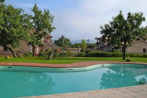 A swimming pool with a tiled edge, surrounded by well-maintained grass and trees. - Tourist Resort, Grosseto (Sorano)