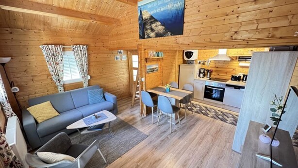 A cozy cabin interior with a living area, dining space, and kitchen. - Wunderschones Blockbohlenhaus am Plauer See (Plau am See)