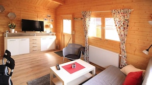 A cozy wooden cabin with a living area, a kitchenette, and a TV. - Wunderschones Blockbohlenhaus am Plauer See (Plau am See)