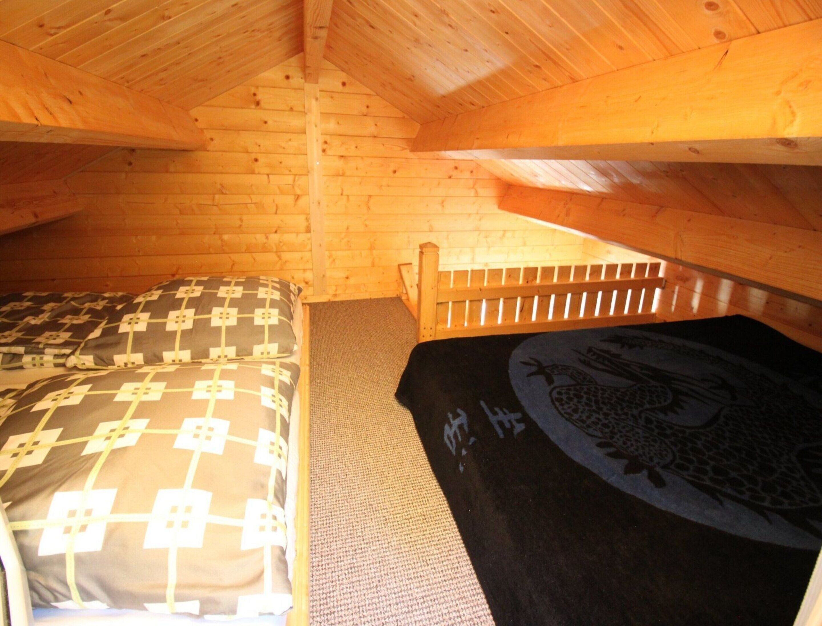 Una stanza piccola e accogliente con un letto singolo, una panca in legno e un soffitto spiovente.