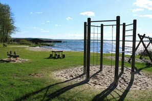 Relax on a serene beach with a wooden swing set and picnic area.