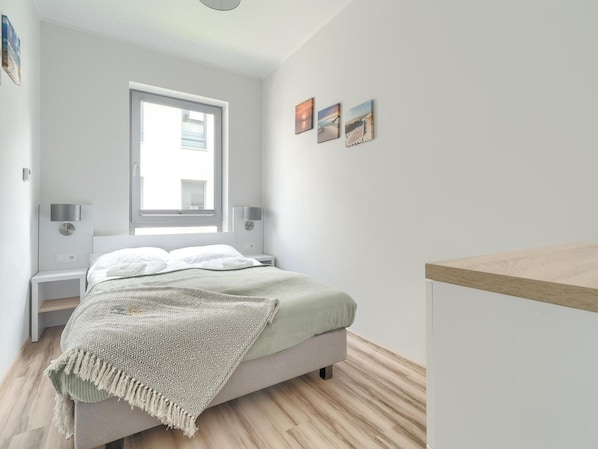 A modern bedroom with a bed, bedside tables, a window, and wall art. - Beautiful Apartment Very Close to the Beach (Rewal)
