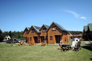 A row of wooden cabins with picnic tables and a small play area. - Terraced House in Rewal Near Baltic Beach (Rewal)
