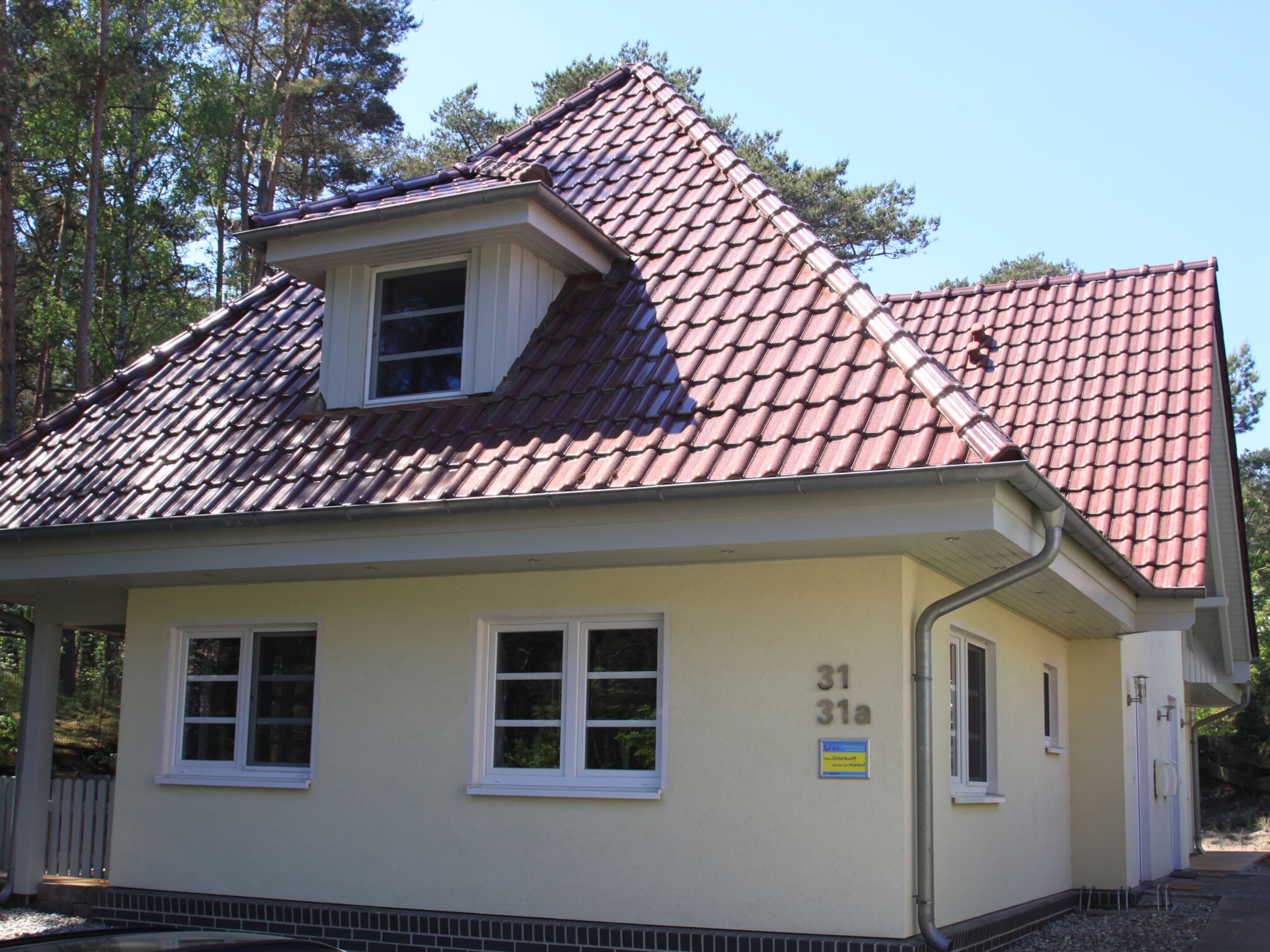 A small, single-story building with a red-tiled roof and a dormer window. The building has a number '31' and '31a' on its facade, indicating it is part of a larger complex.