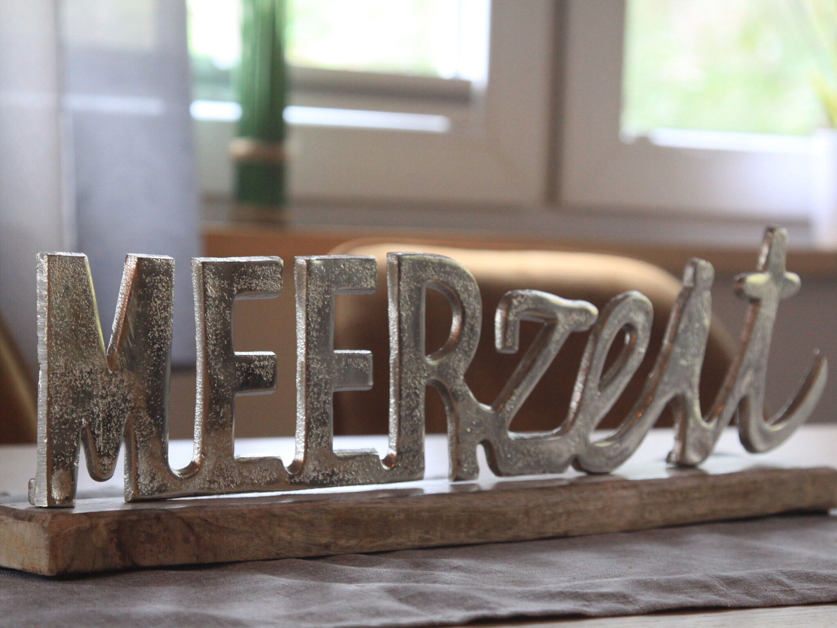 Ein hölzernes Schild mit der Aufschrift 'MEERZELT' in Metallbuchstaben.