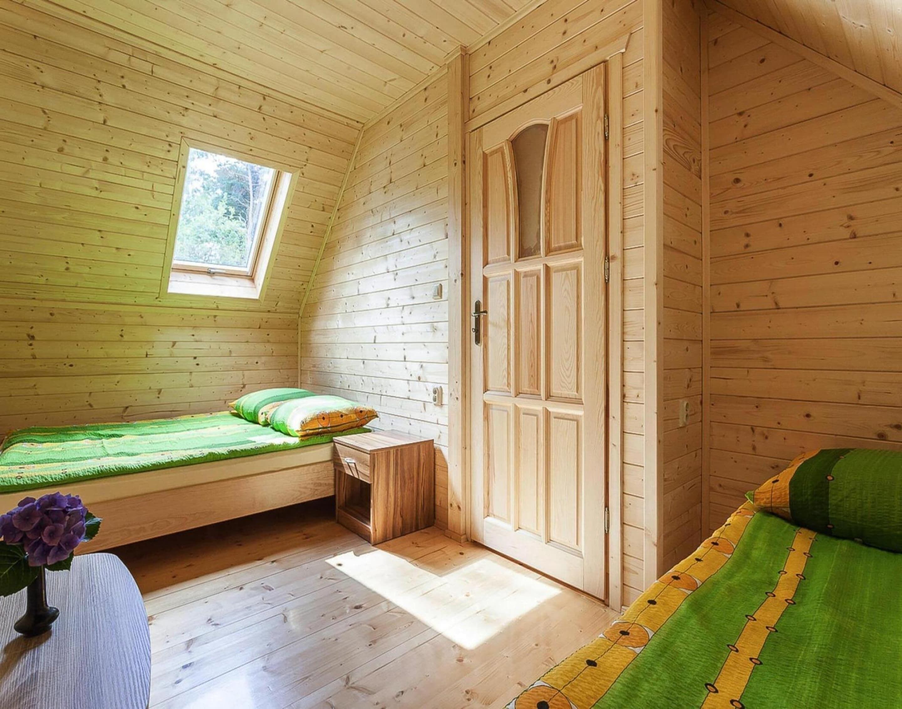 A cozy cabin room with a loft bed, a small desk, and a wardrobe.