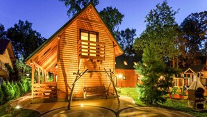 A wooden cabin with a porch, a swing, and a children's play area. - Holiday Home Pobierowo Near Baltic Sea (Rewal)