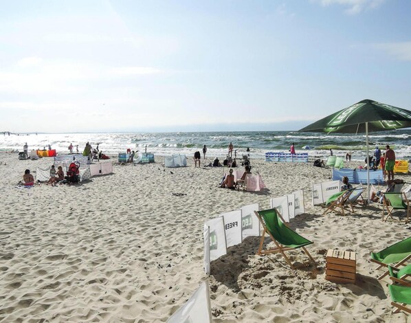 Una playa con arena, sombrillas y gente.
