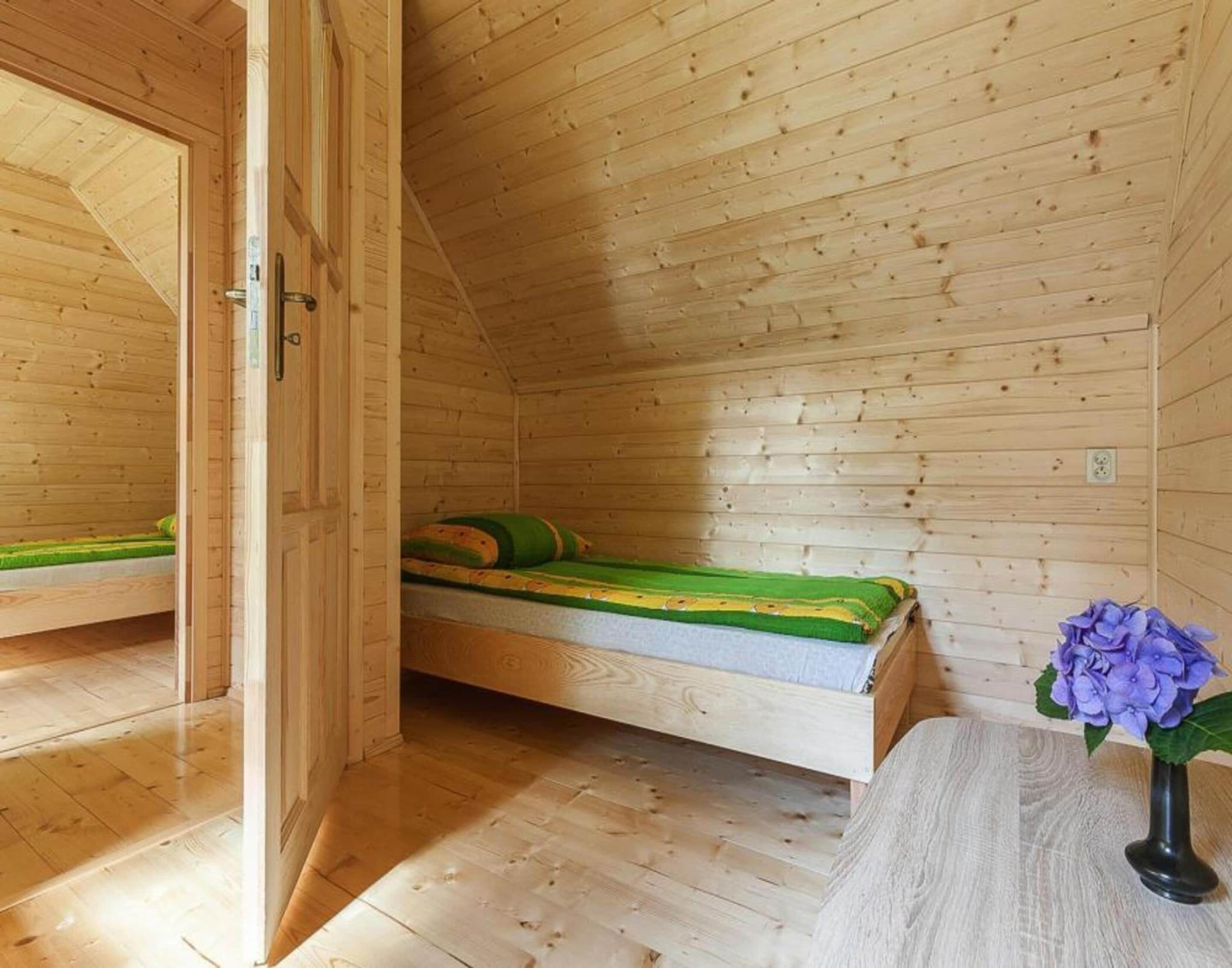 Une pièce de cabane en bois avec deux lits superposés, une petite table et un vase rempli de fleurs.