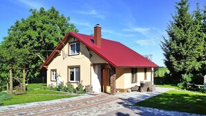 Et toetagers hus med rødt tag, en stenskorsten og en belagt indkørsel.