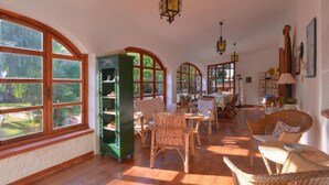 A sunlit room with large windows, wicker furniture, and a green cabinet. - Holiday Home With Private Pool in Fanusa (Syracuse)