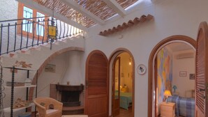 A cozy interior with a fireplace, wicker furniture, and a staircase leading to an upper level. - Holiday Home With Private Pool in Fanusa (Syracuse)