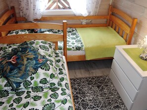 A wooden bed with a green leaf-patterned bedspread and a matching pillow. - Holiday Home in Kolczewo Near Baltic Sea (gmina Wolin)