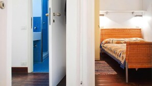 Ein Schlafzimmer mit Bett, einer Tür zu einem Badezimmer und einer kleinen Ablage mit Spiegel.