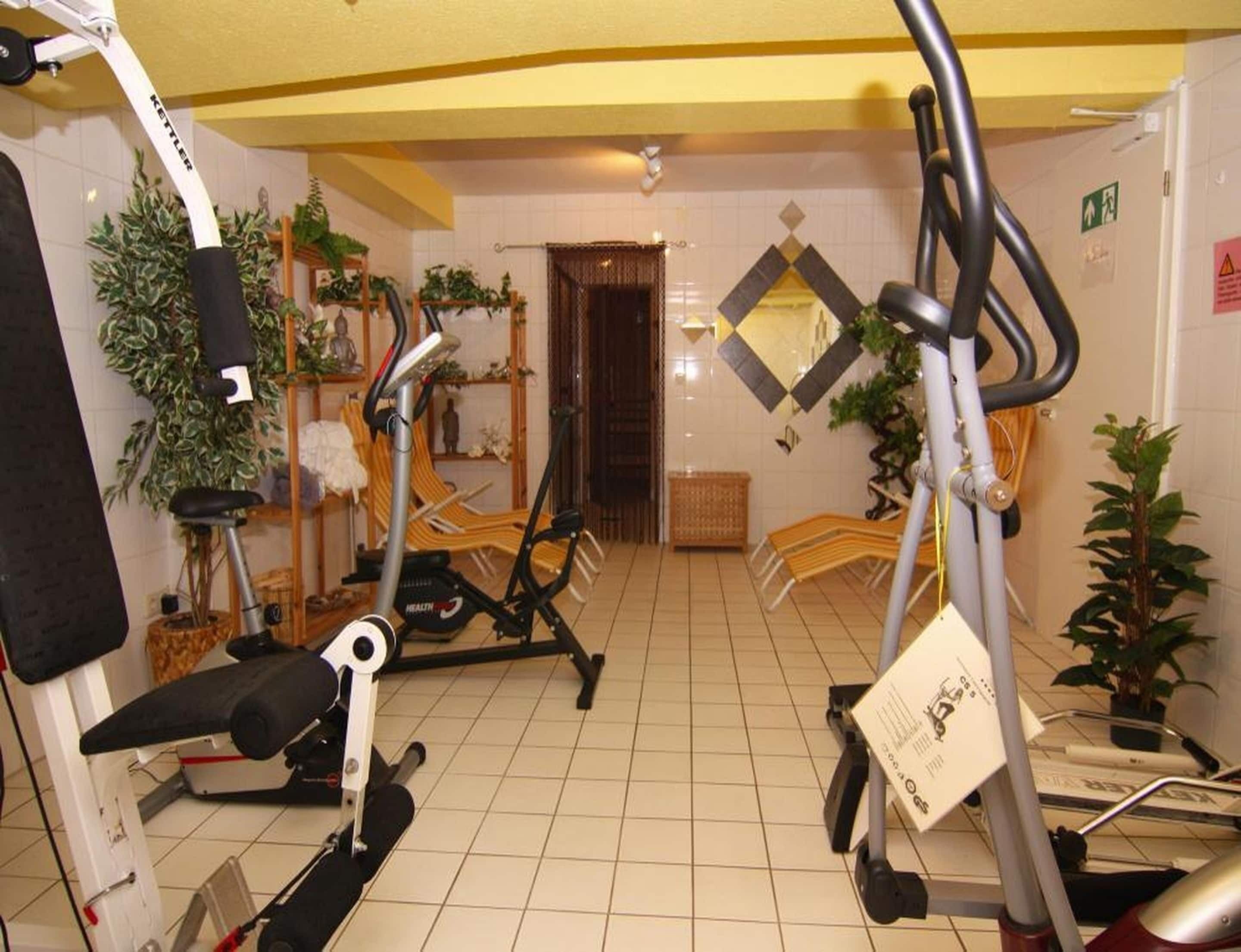 Un gimnasio con equipo de ejercicio, un espejo y plantas en macetas.