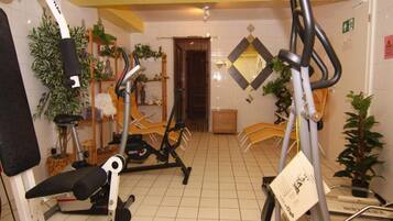 Un gimnasio con equipo de ejercicio, un espejo y plantas en macetas.