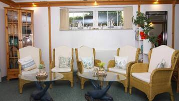 Una habitación con muebles de mimbre, una mesita de centro de vidrio y una ventana con cortinas.
