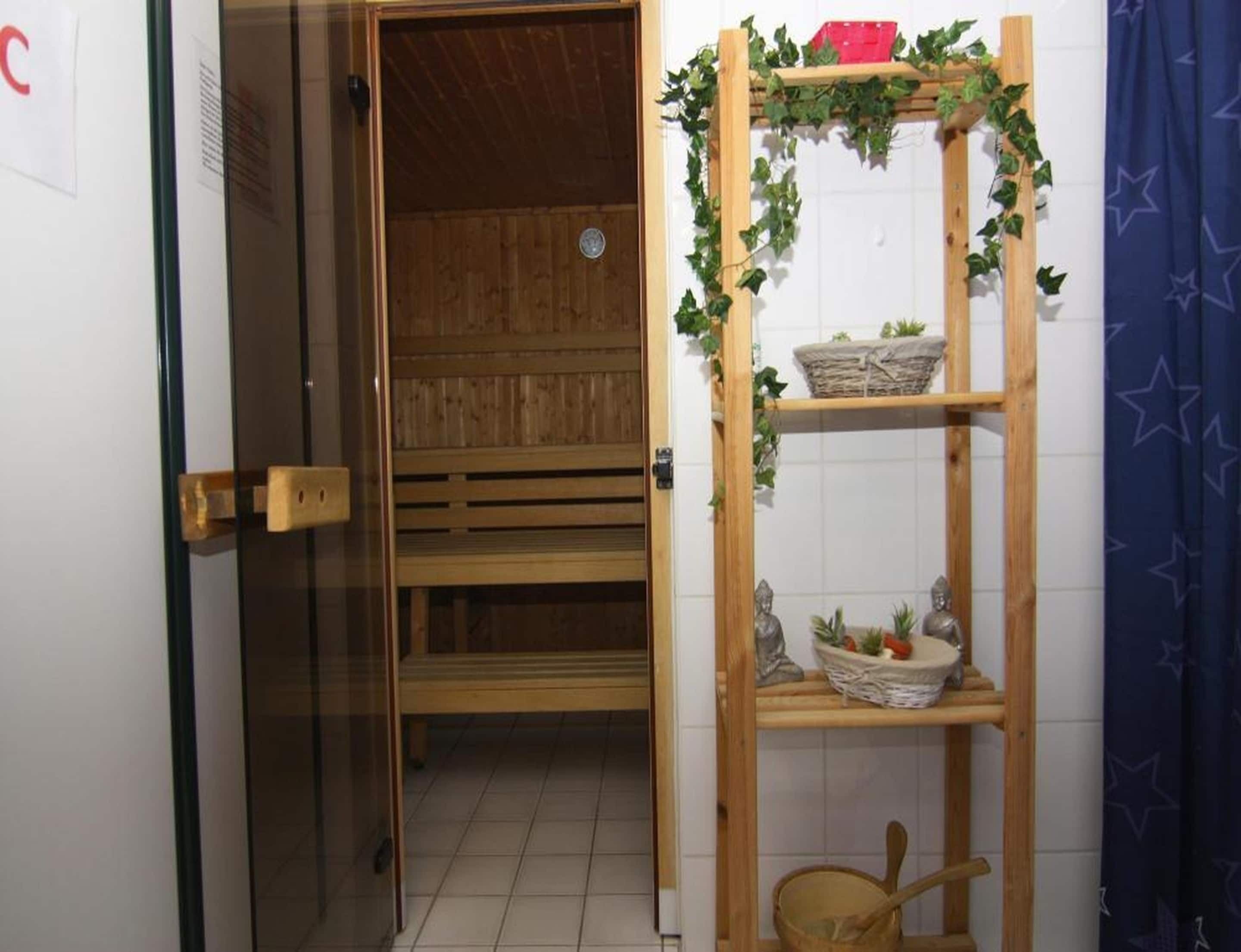 Una sauna con una panca di legno e uno scaffale con piante e un cesto.