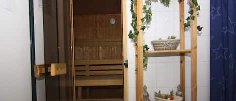 A sauna room with a wooden bench and a shelf with plants and a basket.