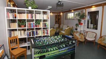Una habitación con mesa de fútbol, estantería y varias sillas.