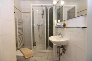 A modern bathroom with a glass-enclosed shower, a white sink, and a toilet.