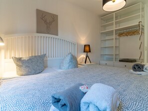A bedroom with a bed, pillows, a bedside lamp, a headboard, a wall-mounted artwork, a wardrobe, and a hanging rack. - Landhaus in Vollerwiek (Vollerwiek)
