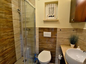 A bathroom with a glass shower enclosure, a toilet, a sink, and a small window with a curtain. - Holiday House by the Lake, Charzykowy-formerly TUI Ferienhaus (Chojnice)
