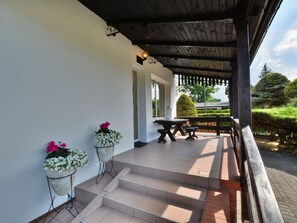 A covered outdoor area with steps leading to a table and chairs, surrounded by white walls and potted plants. - Holiday House by the Lake, Charzykowy-formerly TUI Ferienhaus (Chojnice)