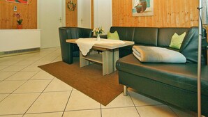 A modern living room with a sofa, a coffee table, and a rug. There are two doors and a painting on the wall.