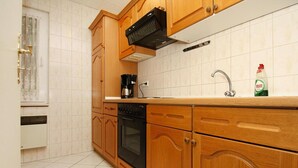 A kitchen with wooden cabinets, a black oven, a coffee maker, and a sink with a faucet.