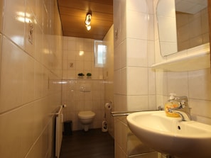 Une salle de bain avec des toilettes, un lavabo et un miroir.