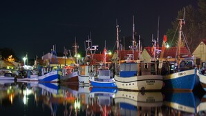 A marina at night with several boats docked, their reflections visible on the water. - Gemutlicher Bungalow in Freest (Kröslin)