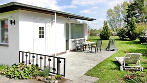 A white building with a covered patio, outdoor seating, and a garden area. - Gemutlicher Bungalow in Freest (Kröslin)